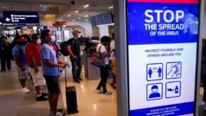 Masked people in airport also showing mask mandate sign